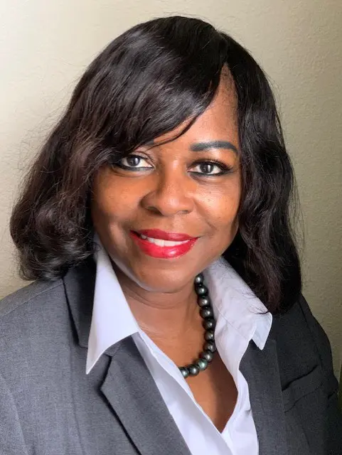 A woman with long black hair wearing a gray suit.